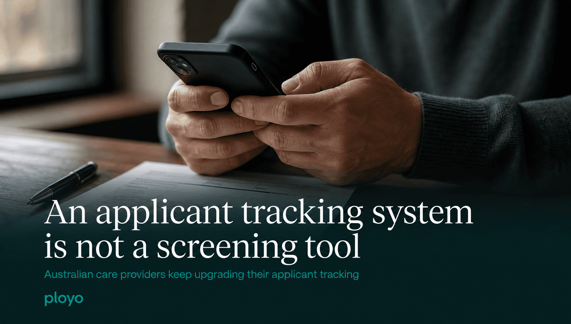 A tight crop of a pair of hands holding a phone over a table, a form and a pen just in frame, no face visible